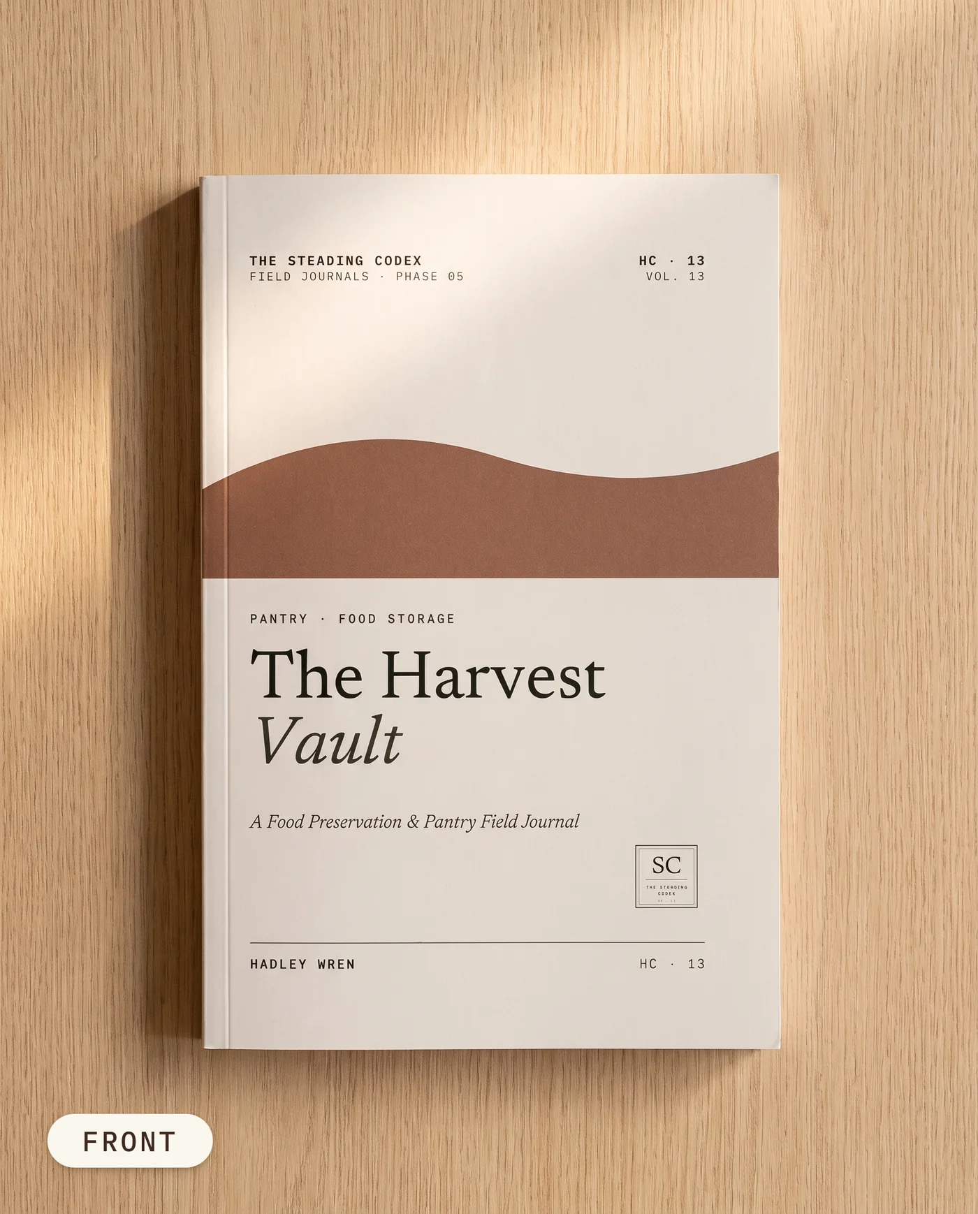 The Harvest Vault pantry and food storage journal — front cover on an oak table