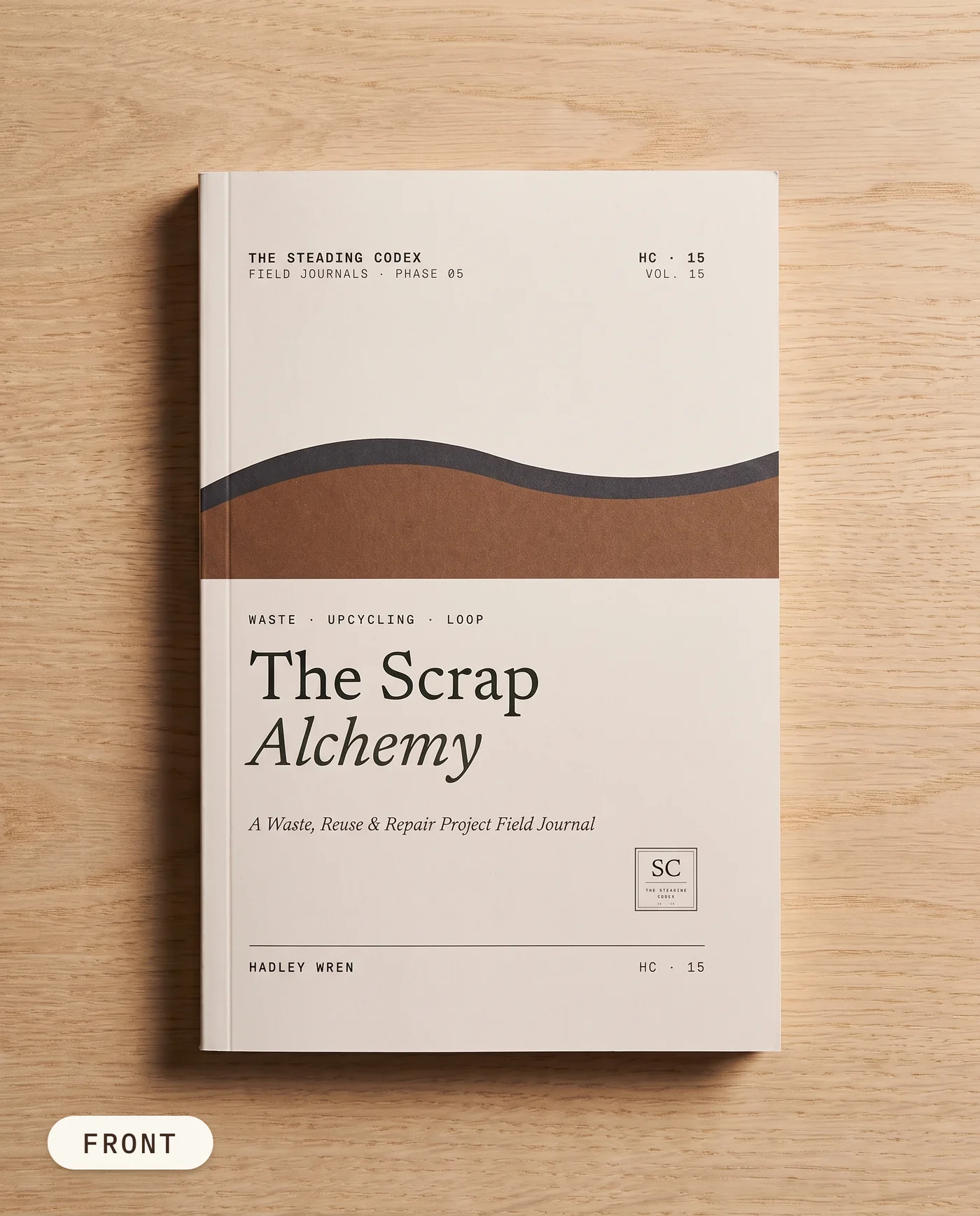 The Scrap Alchemy waste and repair journal — front cover on an oak table