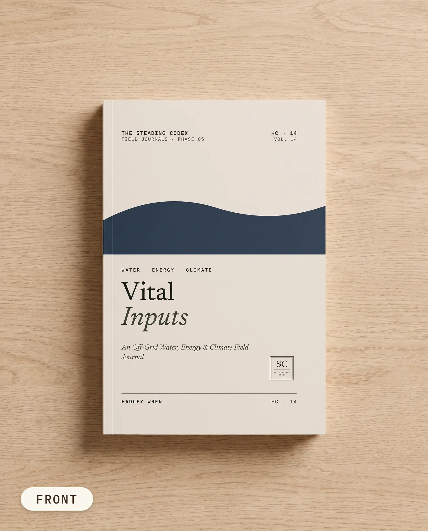 Vital Inputs off-grid water and energy journal — front cover on an oak table