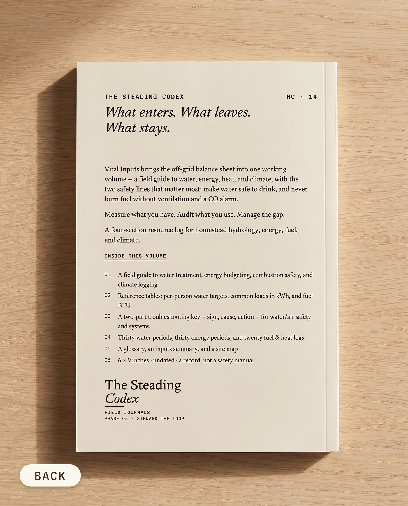 Vital Inputs off-grid water and energy journal — back cover on an oak table